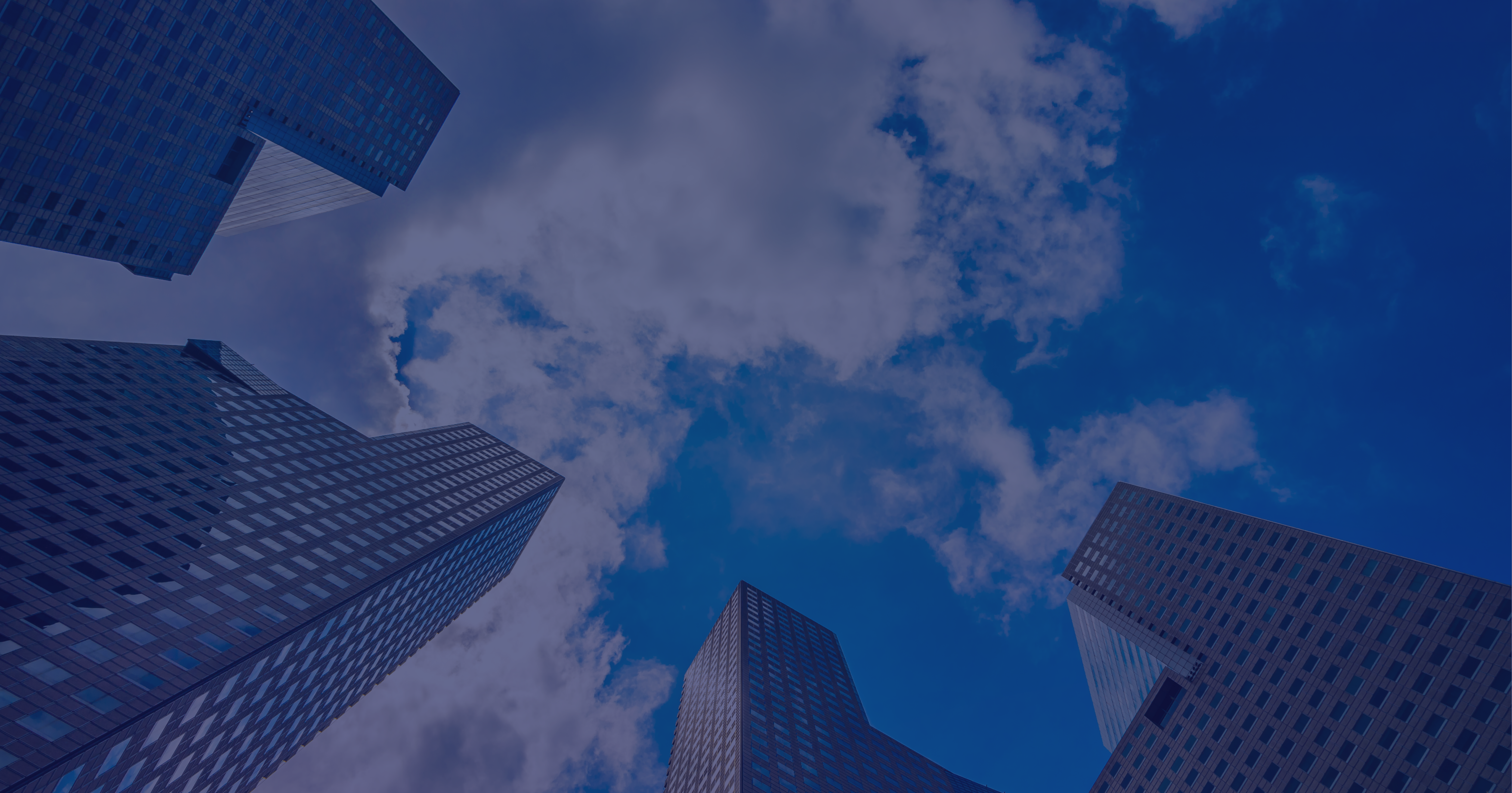 Corporate skyscrapers viewed from below against blue sky with clouds.
