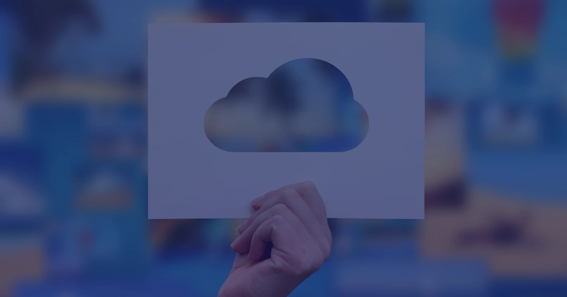 Close-up of a hand holding a paper with a cloud icon cut-out, highlighting AWS cloud services and migration concepts.