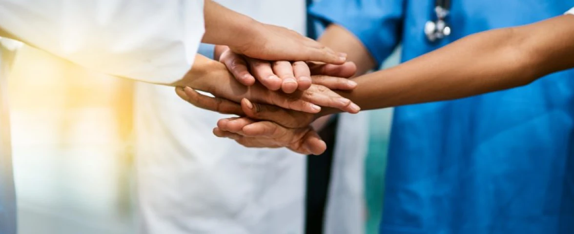 Healthcare team joining hands together showing medical collaboration doctors nurses unity and patient care commitment.