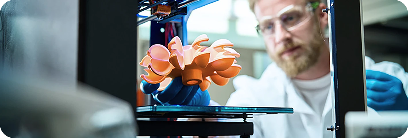 3D printing technology showing scientist in lab coat monitoring complex orange object being manufactured with additive manufacturing process