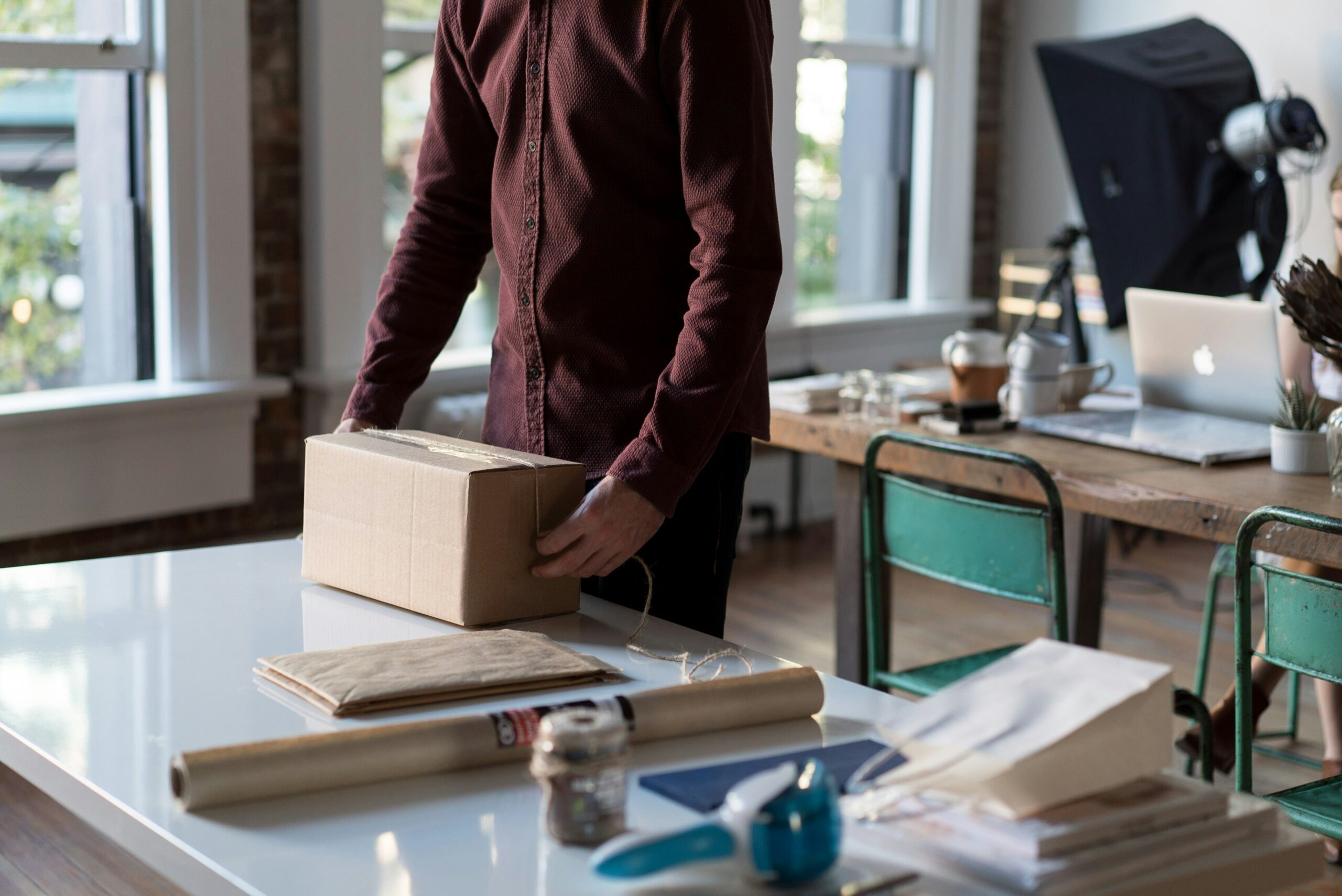 Small business workspace with packed box, shipping supplies, and laptops—highlighting e-commerce or startup operations.